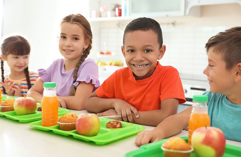 smiling boy and girl having nutritious lunch at school