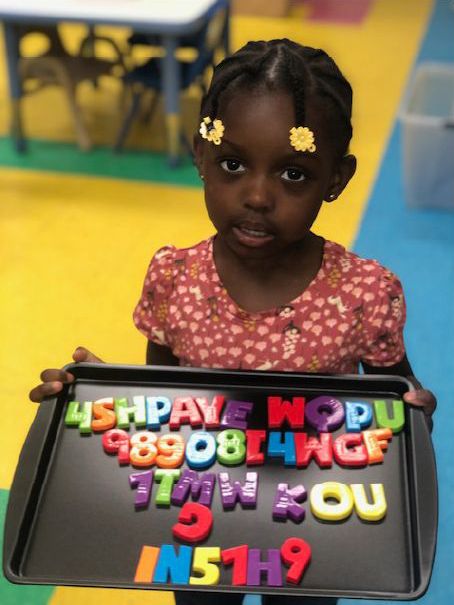 young student showing off her work with the alphabet magnets